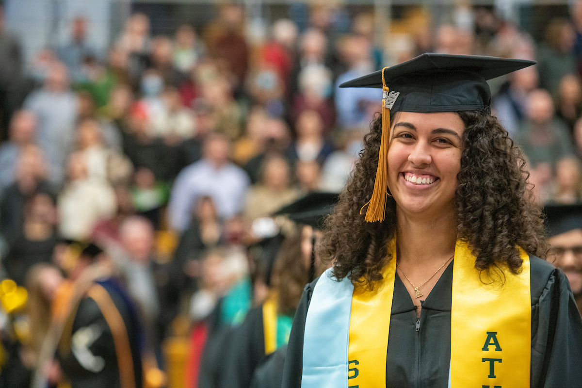 student smiling in front of crowd at graduation